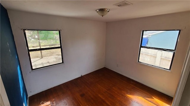 empty room with baseboards, visible vents, and wood finished floors