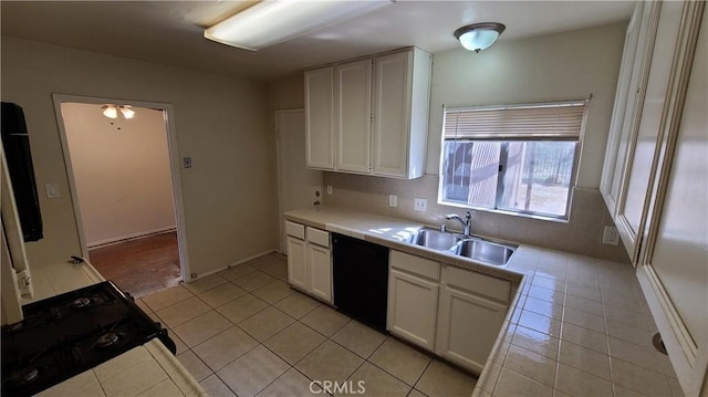 kitchen featuring tile countertops, light tile patterned floors, stove, white cabinets, and a sink