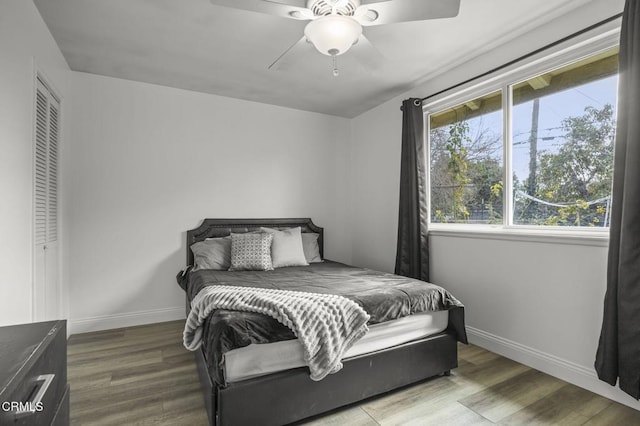 bedroom with a ceiling fan, baseboards, and wood finished floors