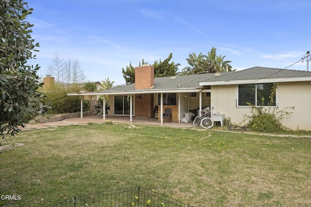 back of property with a yard, a chimney, and a patio