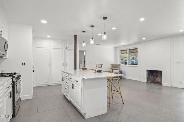 kitchen featuring recessed lighting, stainless steel appliances, a breakfast bar, a kitchen island, and white cabinets