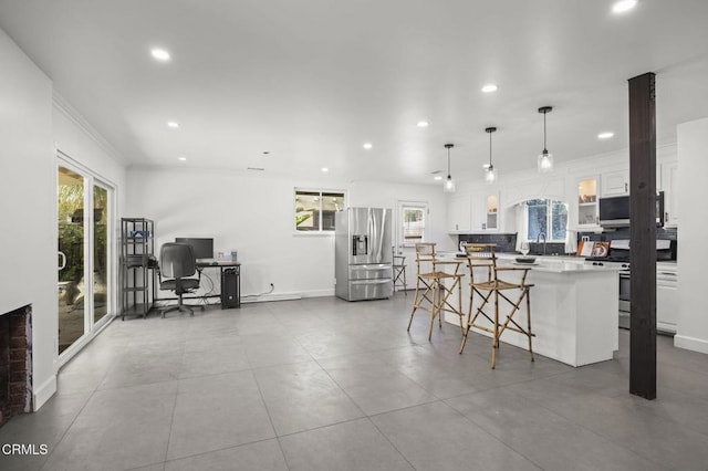 kitchen featuring a center island, appliances with stainless steel finishes, glass insert cabinets, white cabinetry, and a kitchen breakfast bar