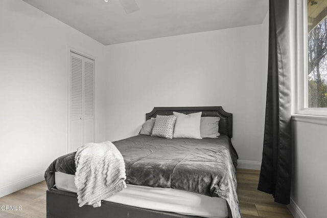 bedroom with a closet, wood finished floors, a ceiling fan, and baseboards