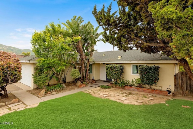 single story home featuring fence, stucco siding, roof with shingles, a front yard, and a mountain view