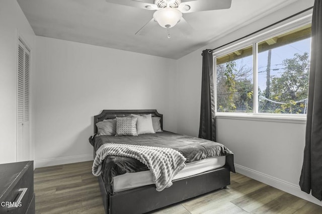 bedroom featuring wood finished floors, baseboards, and a ceiling fan
