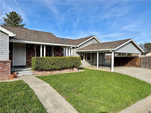 ranch-style house with an attached carport, brick siding, a shingled roof, fence, and a front lawn