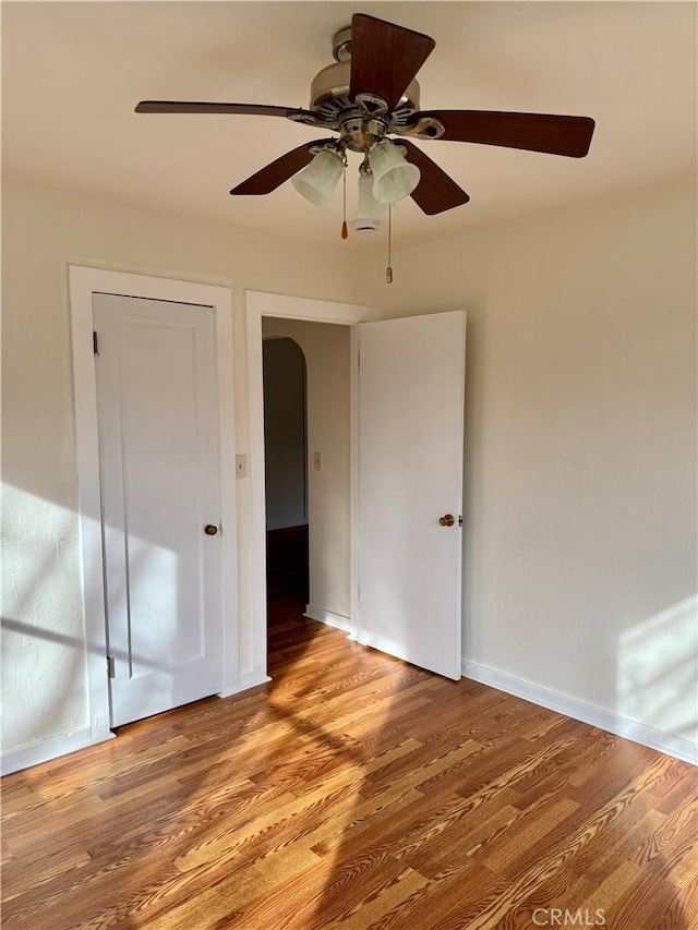 unfurnished bedroom with ceiling fan, light wood finished floors, and baseboards