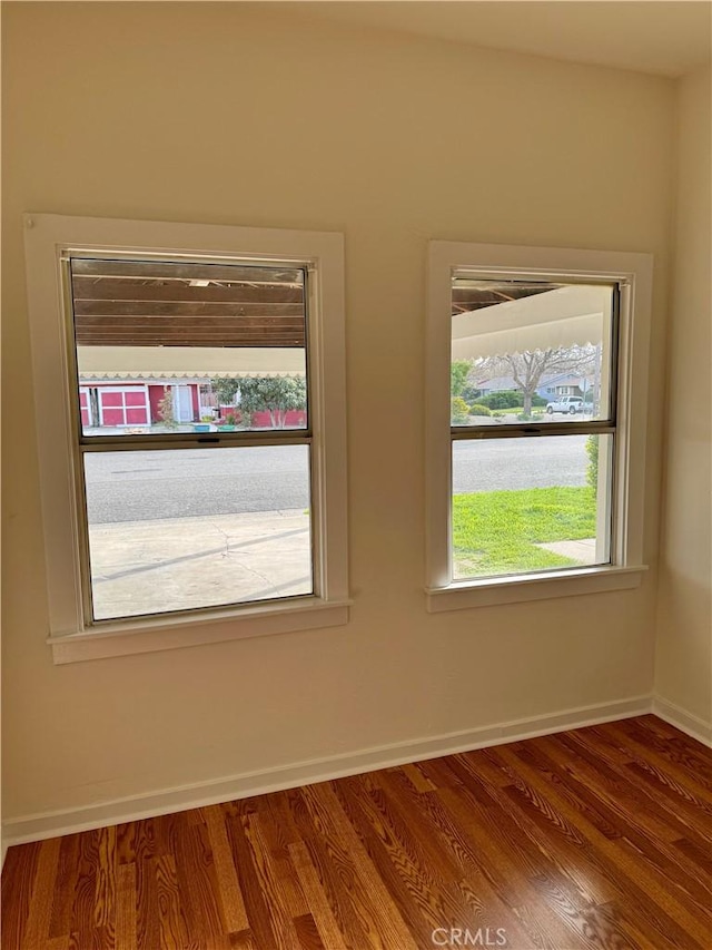 unfurnished room featuring a water view, wood finished floors, and baseboards