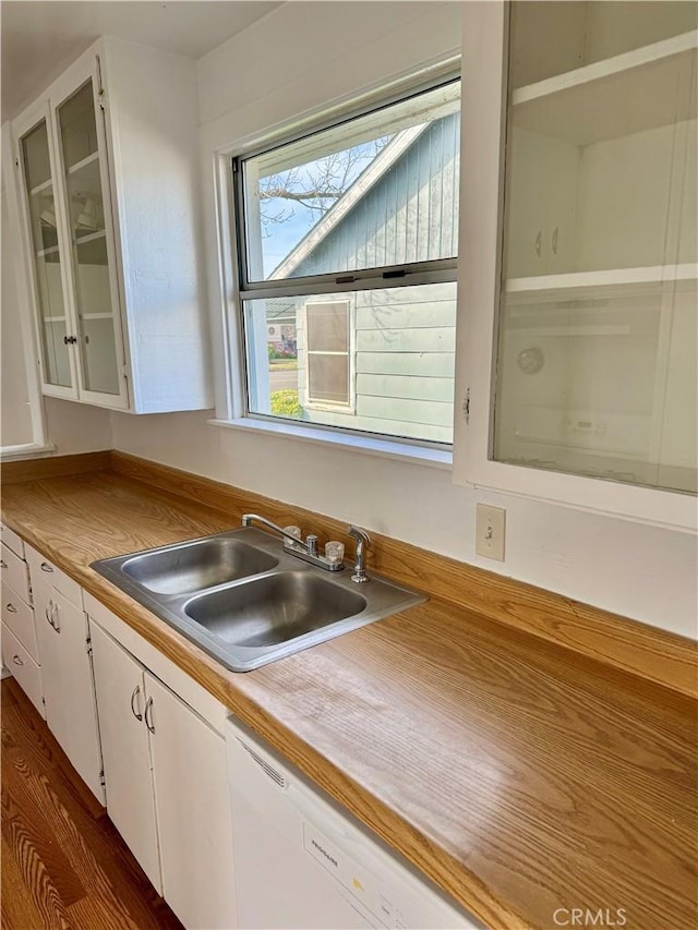 kitchen with dishwasher, glass insert cabinets, light countertops, white cabinetry, and a sink