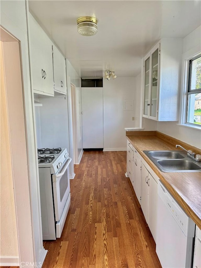 kitchen featuring dark wood finished floors, glass insert cabinets, white cabinets, a sink, and white appliances