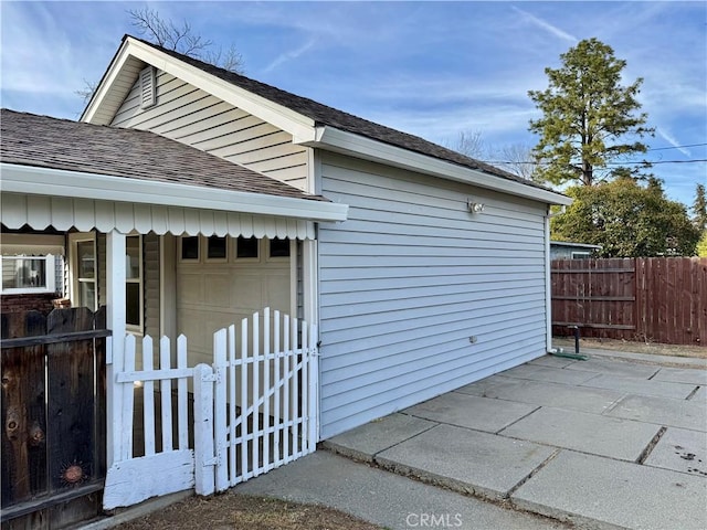 view of property exterior featuring roof with shingles and fence