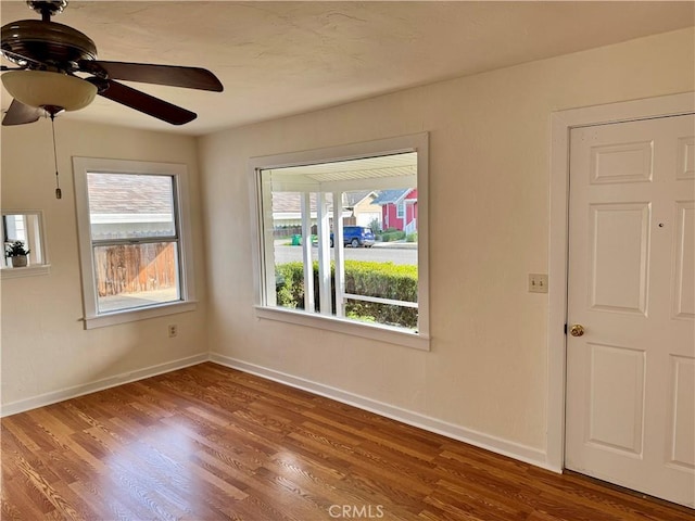 spare room featuring a ceiling fan, baseboards, and wood finished floors