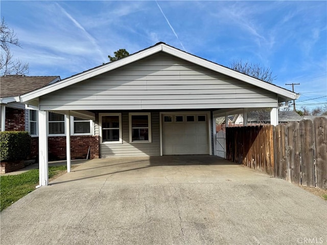 view of front of home featuring brick siding, an attached garage, fence, a carport, and driveway