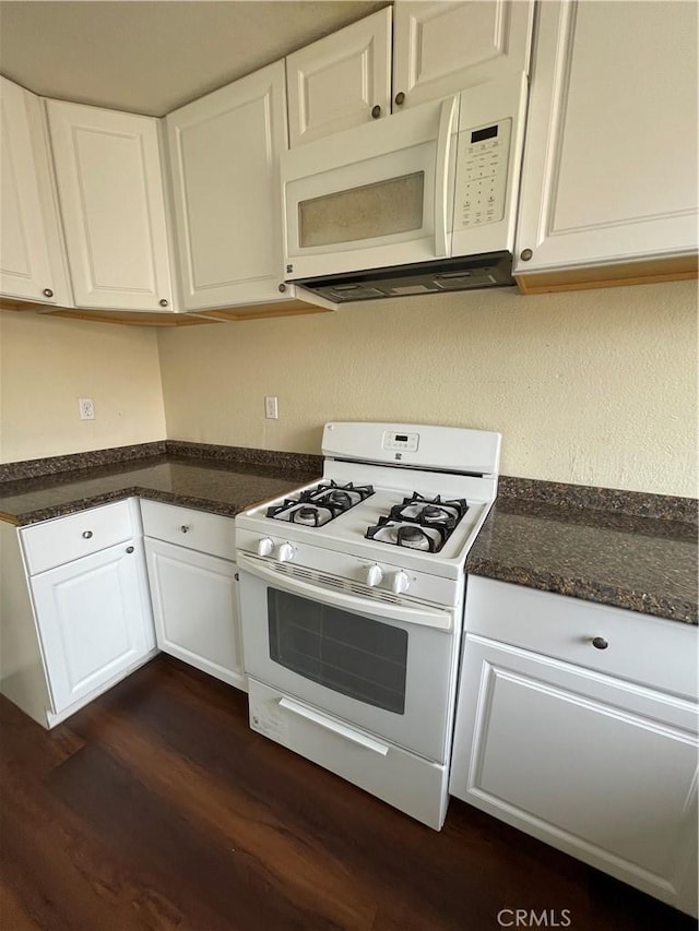 kitchen with dark stone counters, white appliances, dark wood-style flooring, and white cabinetry