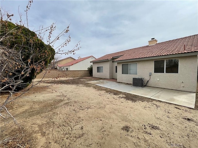 rear view of house featuring fence, a tiled roof, stucco siding, a chimney, and a patio area