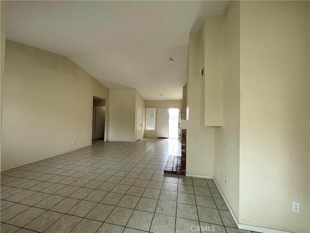 spare room with lofted ceiling, baseboards, and light tile patterned floors