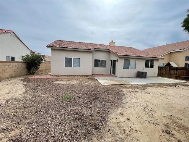 back of house with a patio, a chimney, cooling unit, a fenced backyard, and a tiled roof