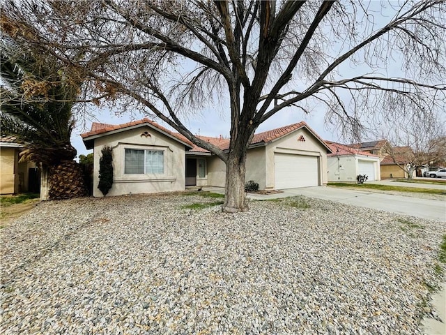 mediterranean / spanish home with a garage, a tiled roof, concrete driveway, and stucco siding