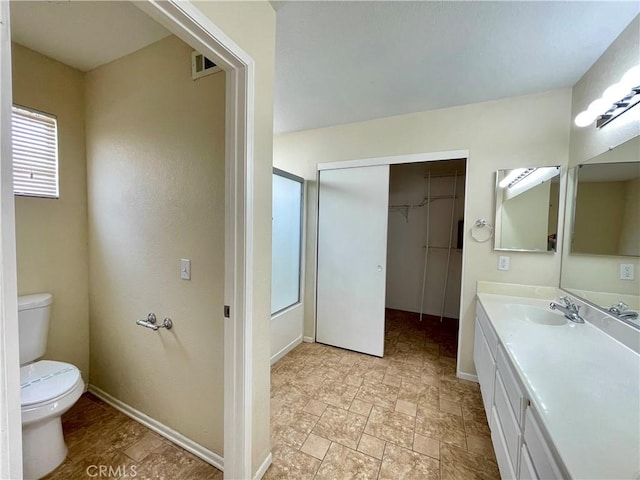 full bathroom with stone finish floor, vanity, toilet, and baseboards