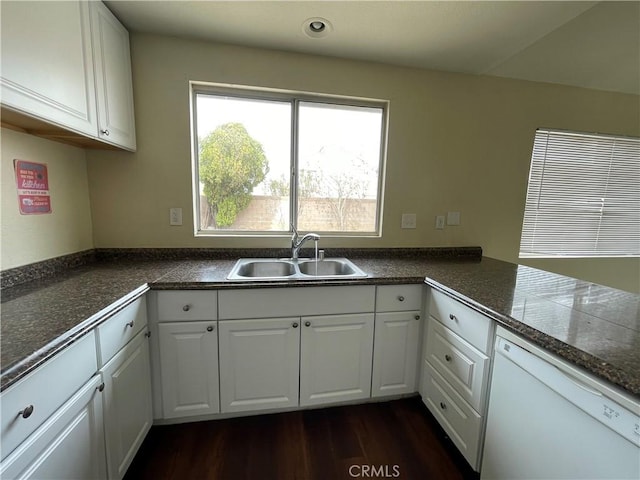 kitchen featuring dark countertops, white cabinets, white dishwasher, and a sink