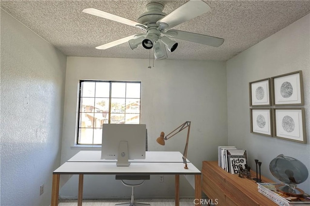 office area featuring a textured ceiling, a textured wall, and a ceiling fan