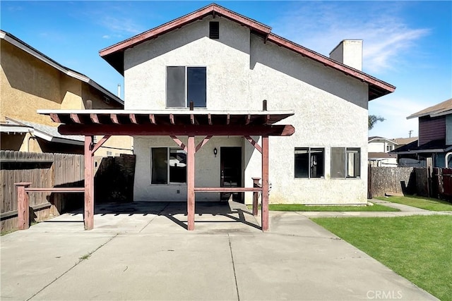 rear view of property with stucco siding, fence, and a patio