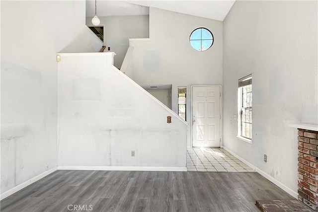 entrance foyer with high vaulted ceiling, stairs, baseboards, and wood finished floors