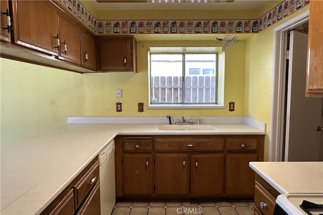 kitchen with white dishwasher, light countertops, and a sink