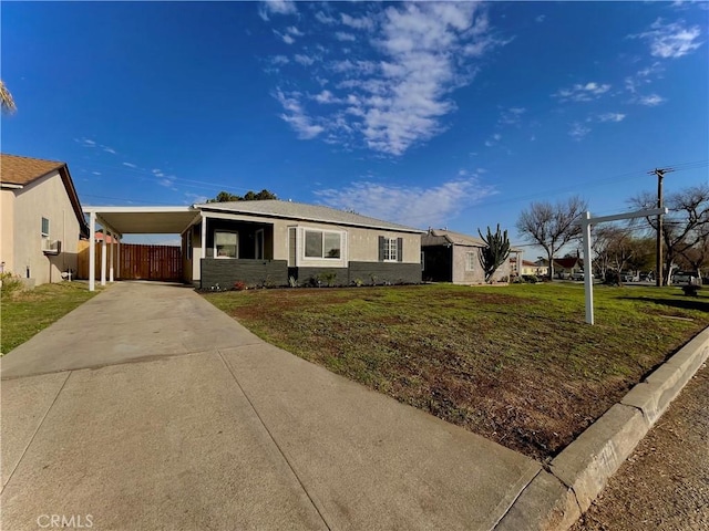 view of front of home with concrete driveway, a carport, a front lawn, and fence