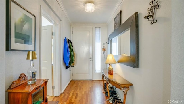 doorway to outside featuring ornamental molding, light wood-style flooring, and baseboards