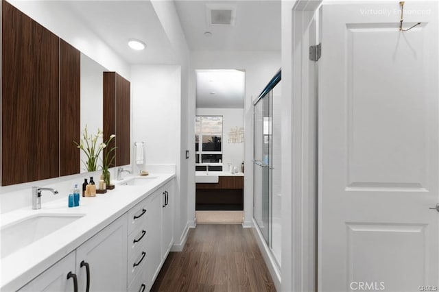 bathroom with double vanity, a stall shower, and a sink