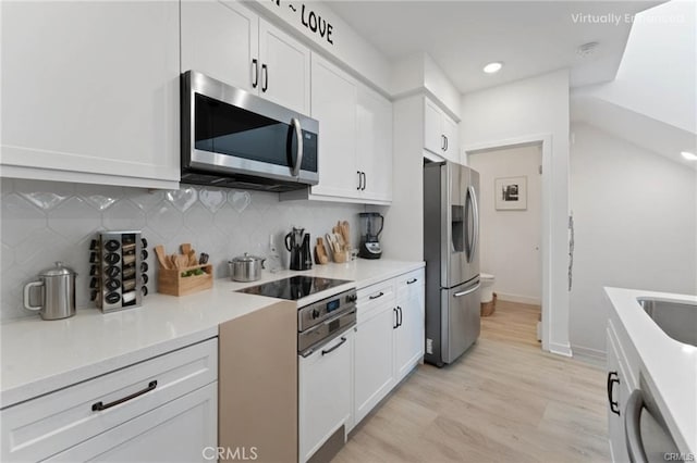 kitchen with stainless steel appliances, light countertops, white cabinets, tasteful backsplash, and light wood-type flooring