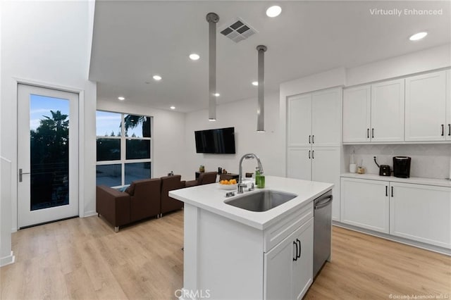 kitchen with visible vents, a sink, light wood-type flooring, white cabinets, and stainless steel dishwasher