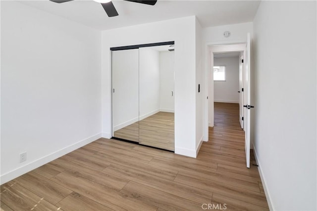 unfurnished bedroom featuring a ceiling fan, light wood-type flooring, a closet, and baseboards