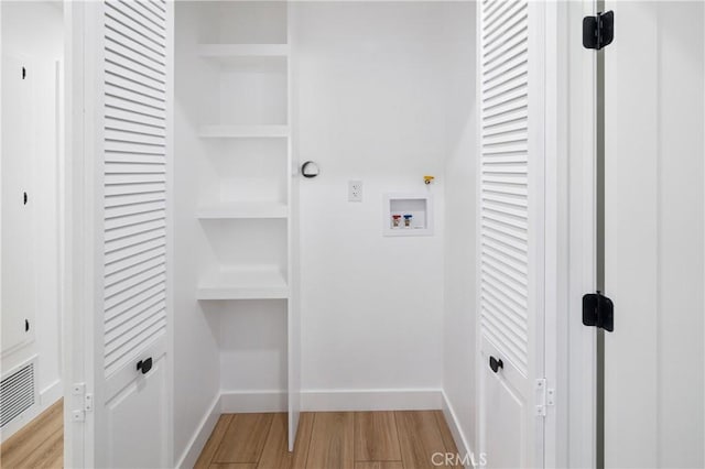 washroom with baseboards, visible vents, hookup for a washing machine, light wood-type flooring, and built in shelves