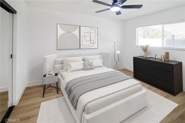 bedroom with light wood-type flooring, baseboards, and a ceiling fan