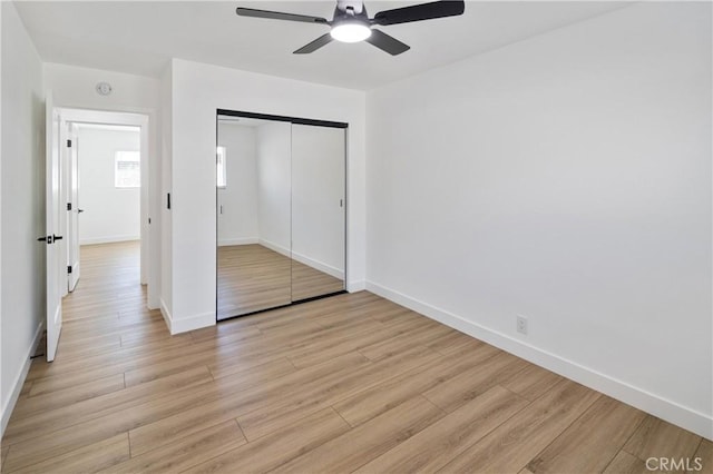 unfurnished bedroom featuring light wood finished floors, a ceiling fan, baseboards, and a closet