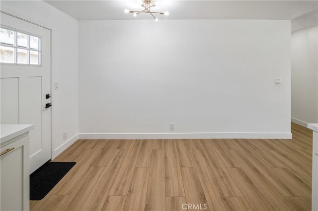 entryway featuring light wood finished floors, baseboards, and an inviting chandelier