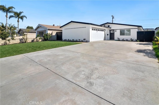 view of front of home featuring a front yard, driveway, an attached garage, and fence