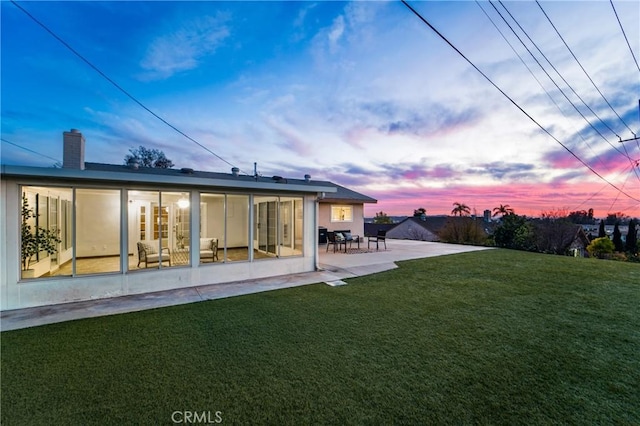 back of property featuring a patio, a yard, and a chimney