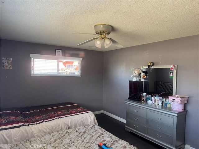 bedroom featuring ceiling fan, a textured ceiling, and baseboards