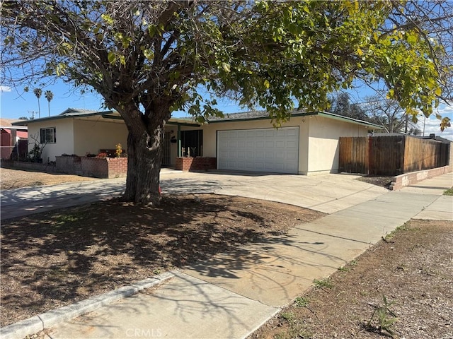 ranch-style house featuring concrete driveway, an attached garage, fence, and stucco siding