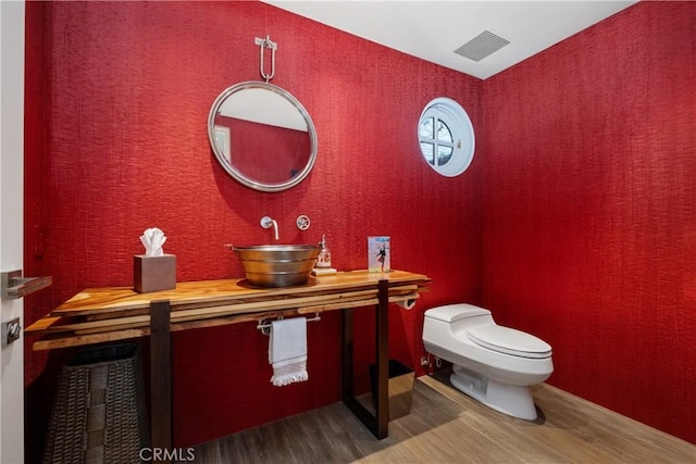 504 Evening Star Ln, Newport Beach, CA 92660 - half bathroom featuring visible vents, toilet, a sink, wood finished floors, and wallpapered walls
