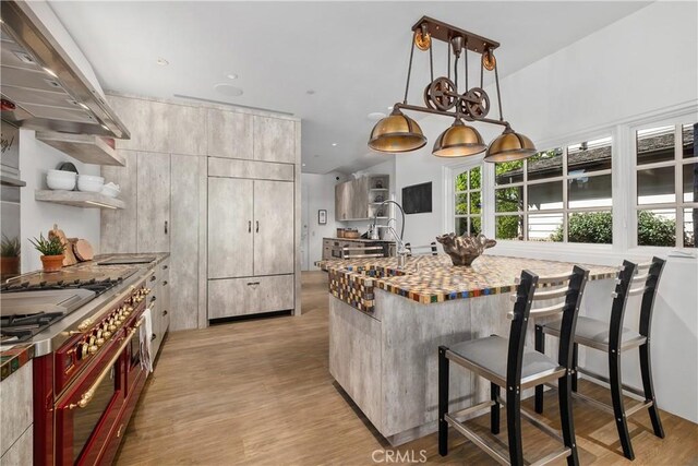 504 Evening Star Ln, Newport Beach, CA 92660 - kitchen with a breakfast bar, hanging light fixtures, a sink, light wood-type flooring, and exhaust hood