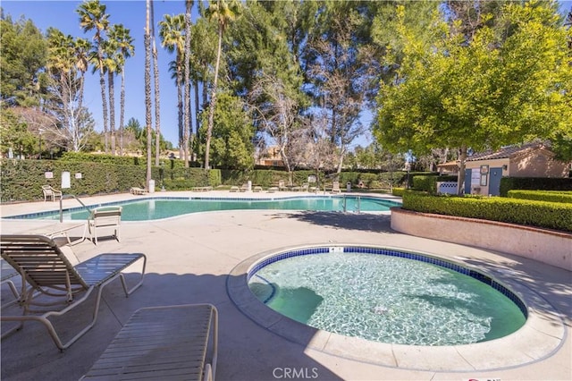 community pool with a community hot tub, a patio area, and fence