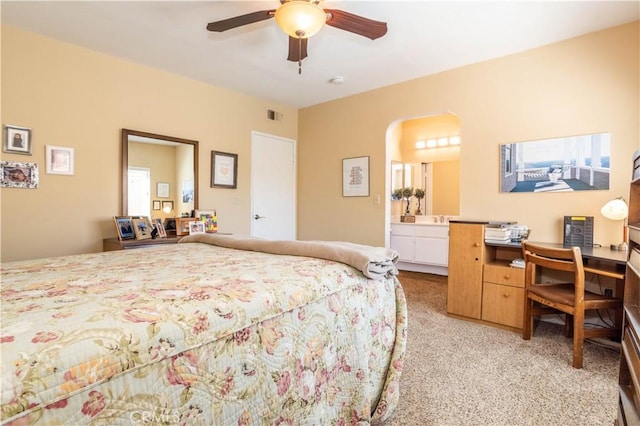 bedroom with arched walkways, visible vents, ensuite bathroom, light carpet, and ceiling fan