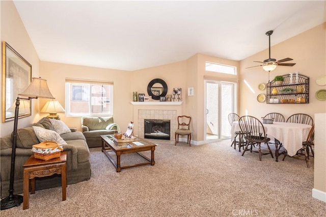 carpeted living room with a tiled fireplace, a ceiling fan, and baseboards