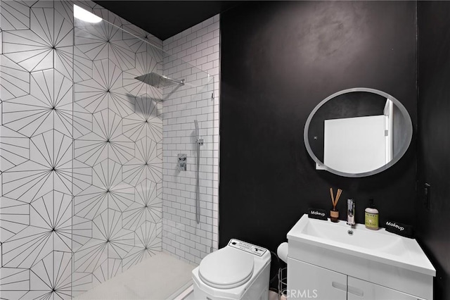 full bathroom featuring vanity, a tile shower, and toilet