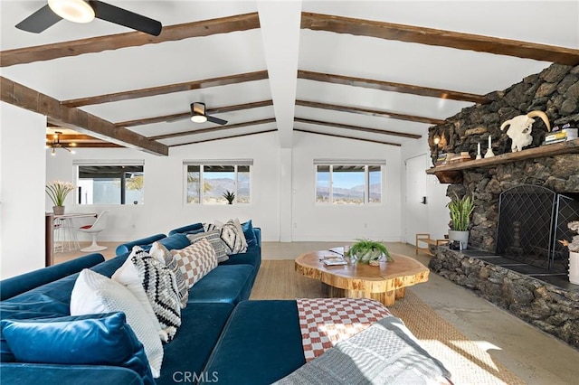 living area with vaulted ceiling with beams, a wealth of natural light, a fireplace, and ceiling fan