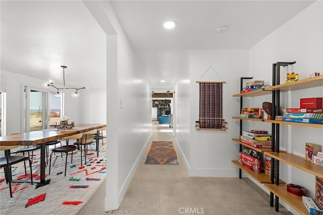 hallway with finished concrete floors, baseboards, a notable chandelier, and recessed lighting